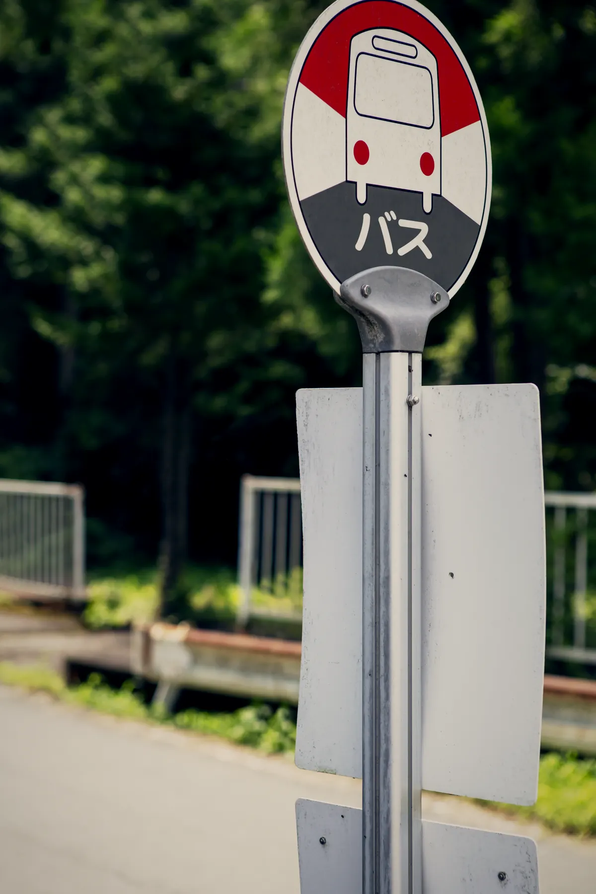 山あいの道ばたに立つバス停の標識