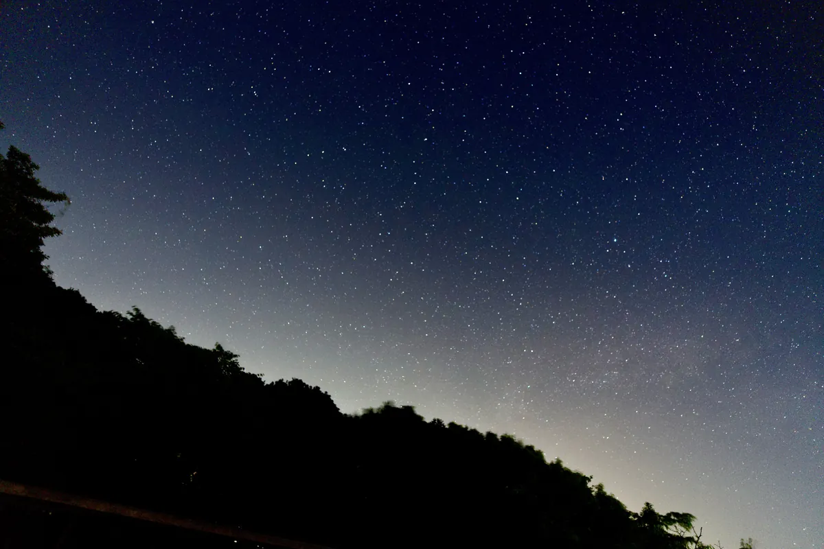 月のない夜空に広がる星と山影